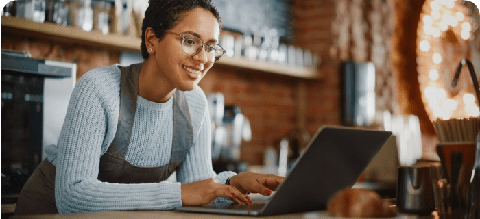 Atendente de restaurante usando o chatbot WhatsApp da OlaClick no notebook